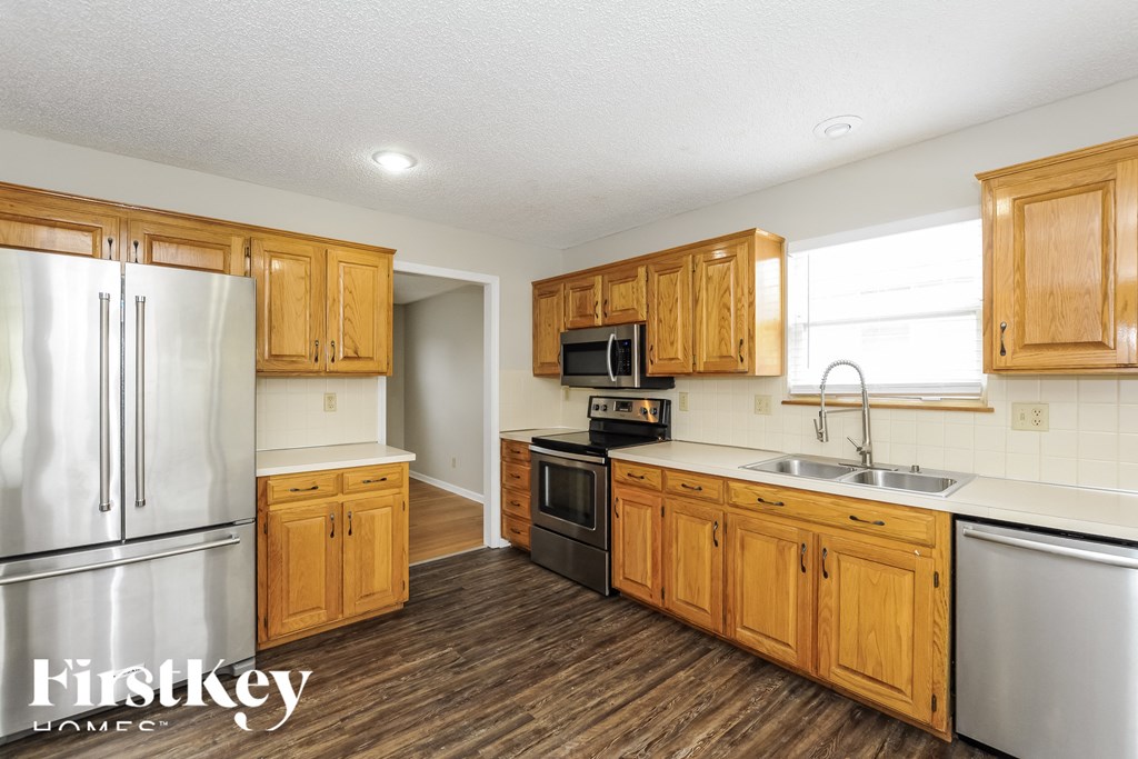 A kitchen with wooden cabinets and a stainless steel refrigerator.