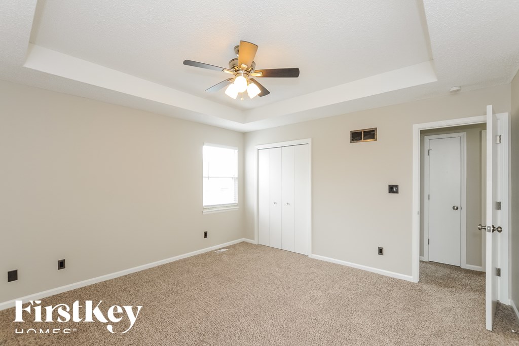 A spacious room with a ceiling fan and two doors.