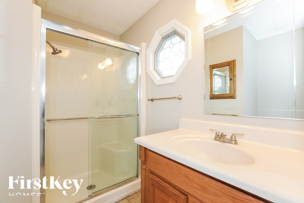 A bathroom with a white sink and a shower with a glass door.