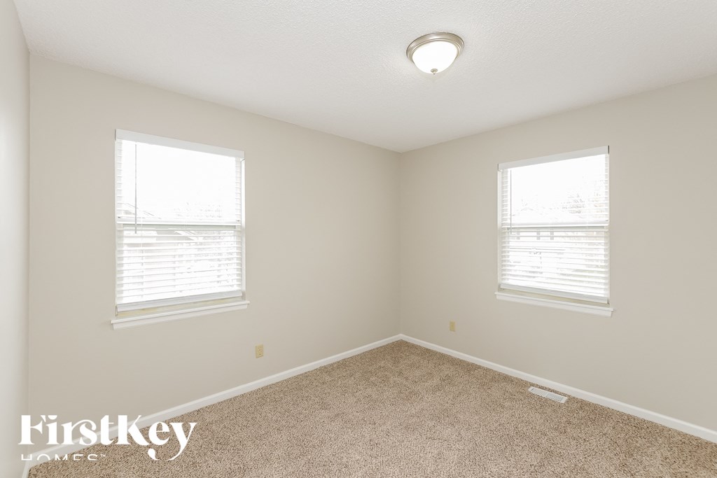 A room with two windows and a carpeted floor.