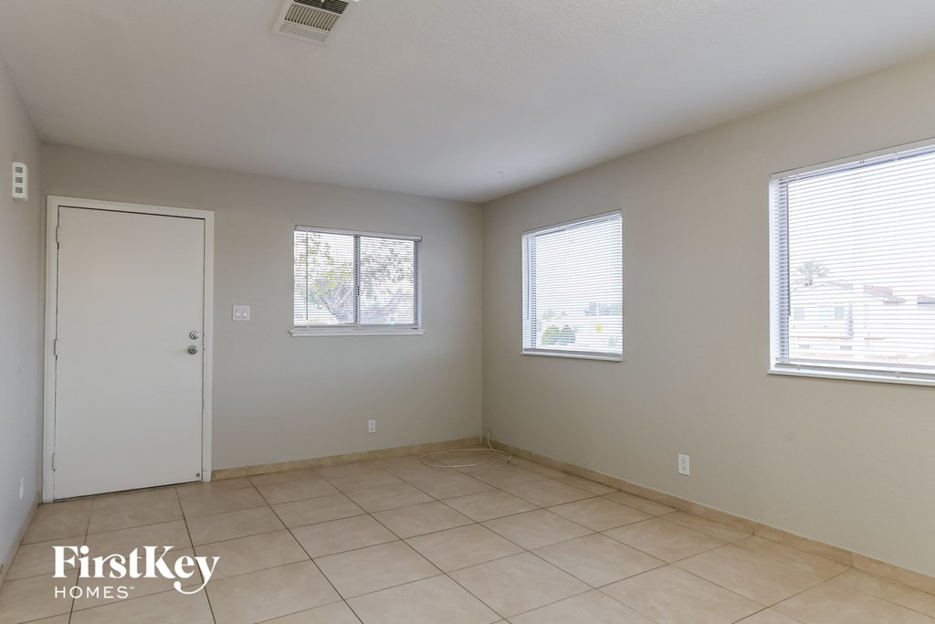 a room with a tiled floor and a door and three windows