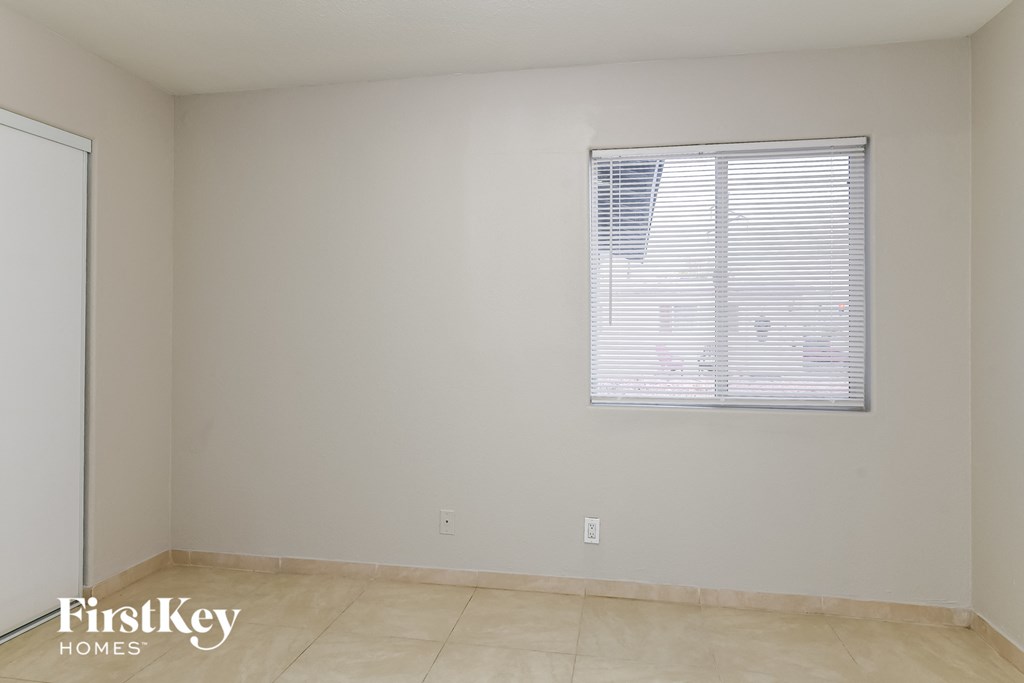 the living room of an empty house with a window and a tiled floor