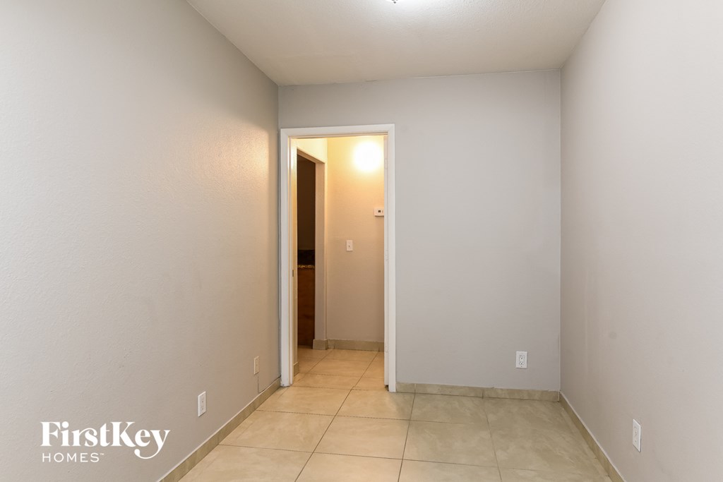 a hallway with a door to a closet and a tiled floor