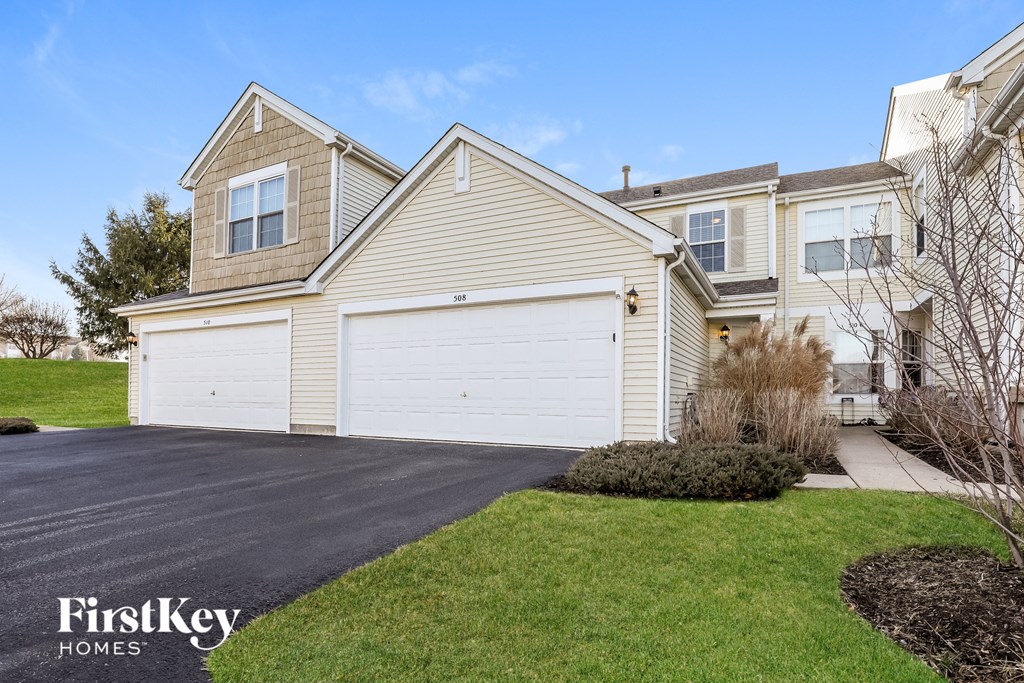 a yellow house with a white garage door in front of a green lawn