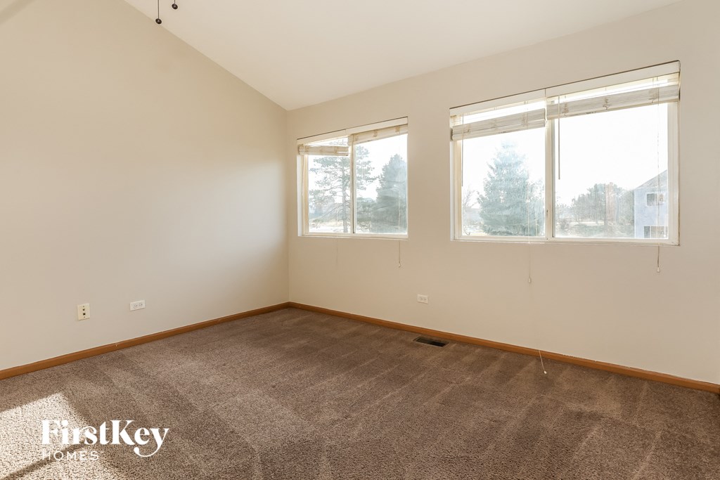 a living room with carpet and three windows