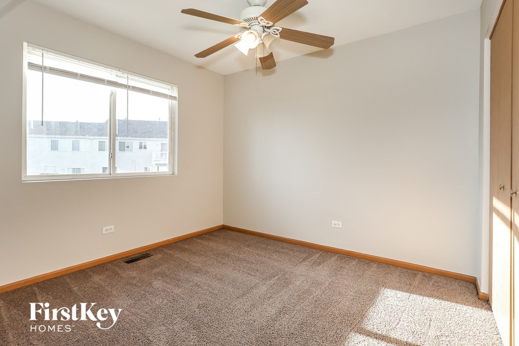 an empty room with a ceiling fan and a window