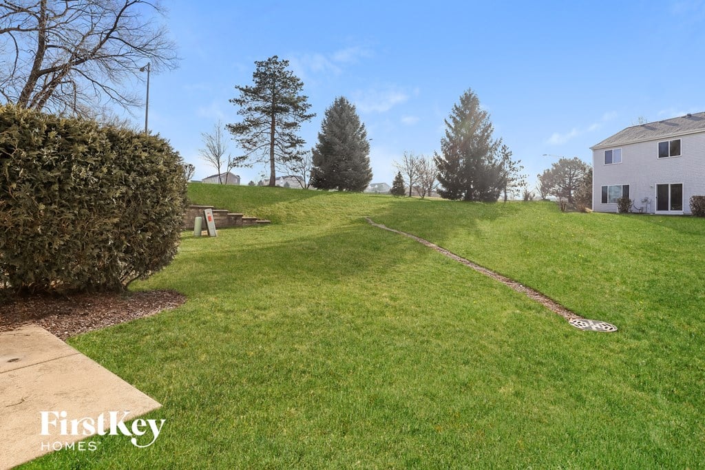 a yard with a house and a hill with grass