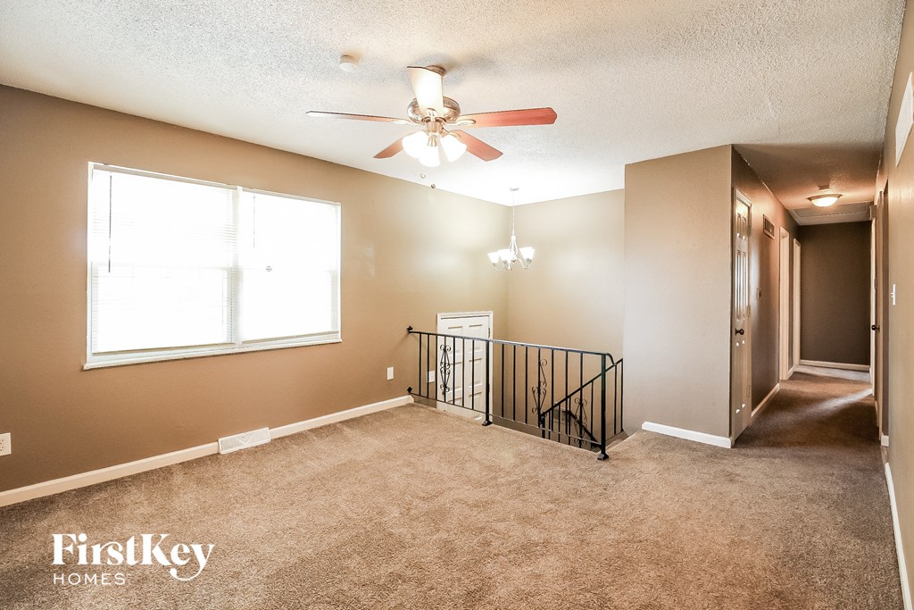 an empty living room with a ceiling fan and a window