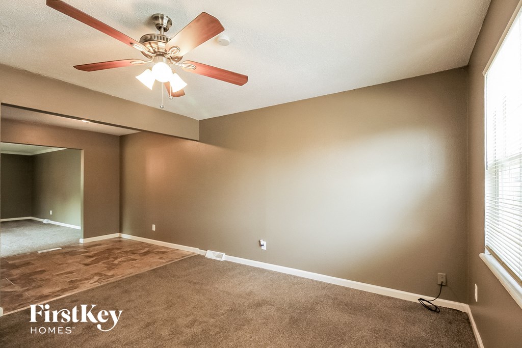 an empty living room with a ceiling fan