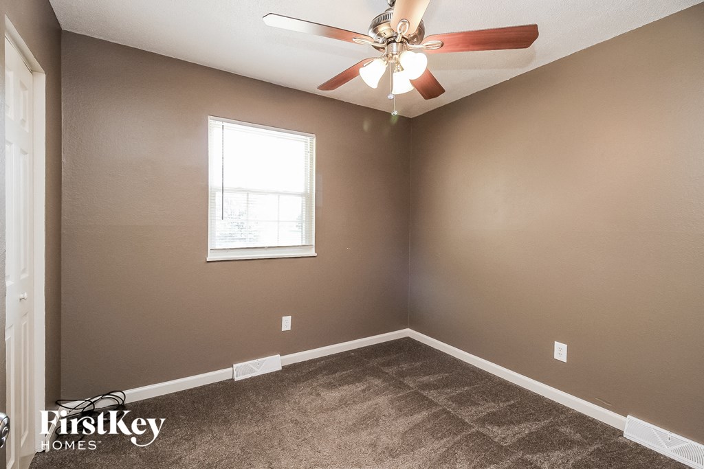 an empty bedroom with a ceiling fan and a window
