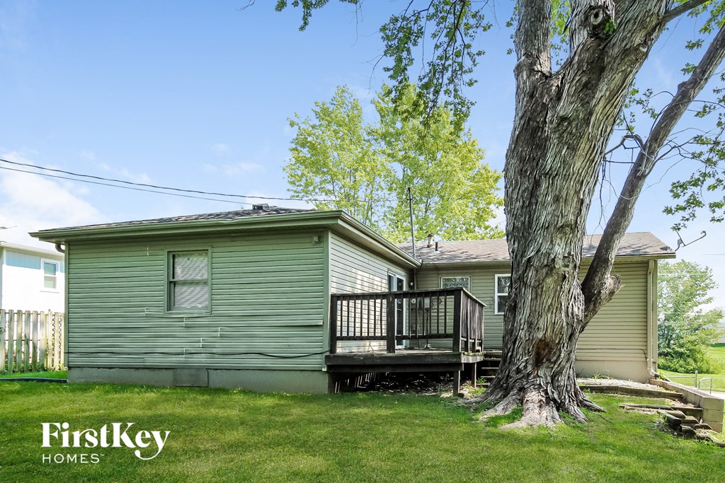 a green house with a deck next to a tree