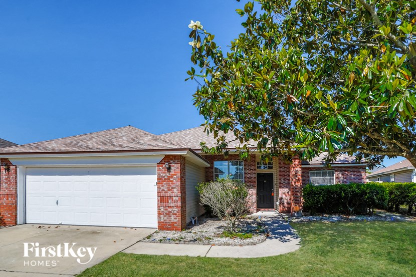 A house with a garage door and a tree in front.
