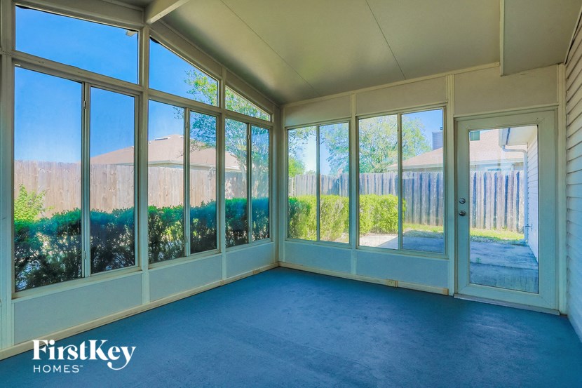 A sunny room with a view of a fence and trees.
