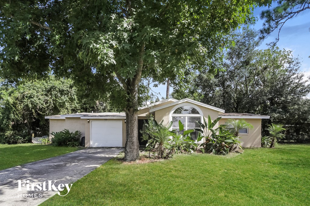 a small tan house with a tree in the yard