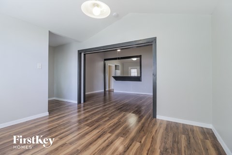 the living room and dining room of an apartment with wood flooring and white walls
