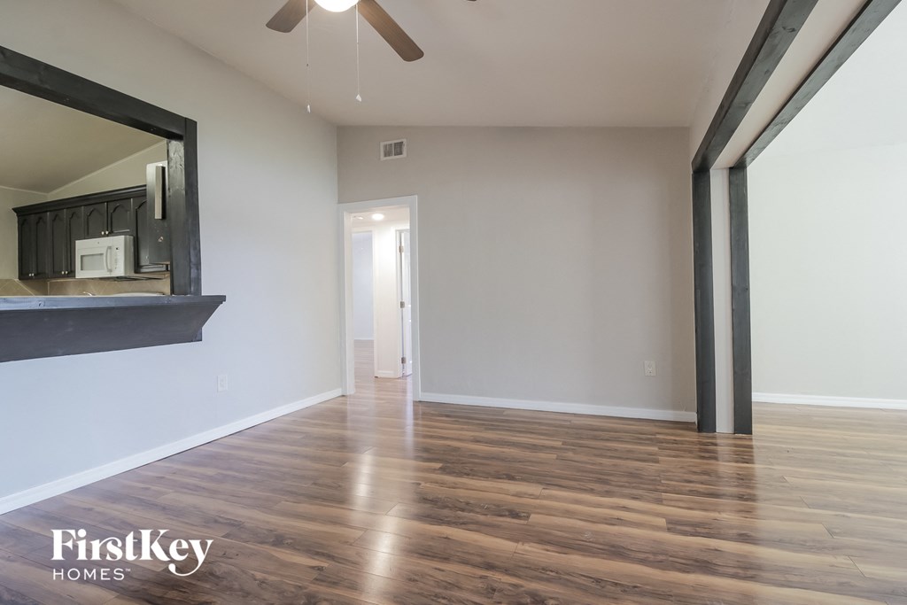 an empty living room with wood flooring and a ceiling fan
