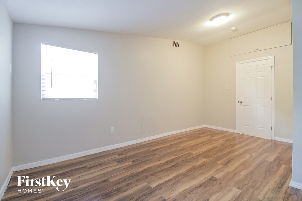 the living room of an apartment with wood flooring and a window