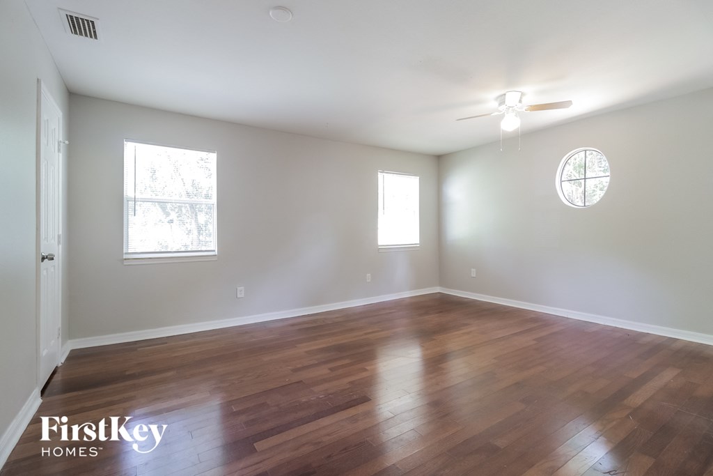 an empty living room with wood floors and a ceiling fan