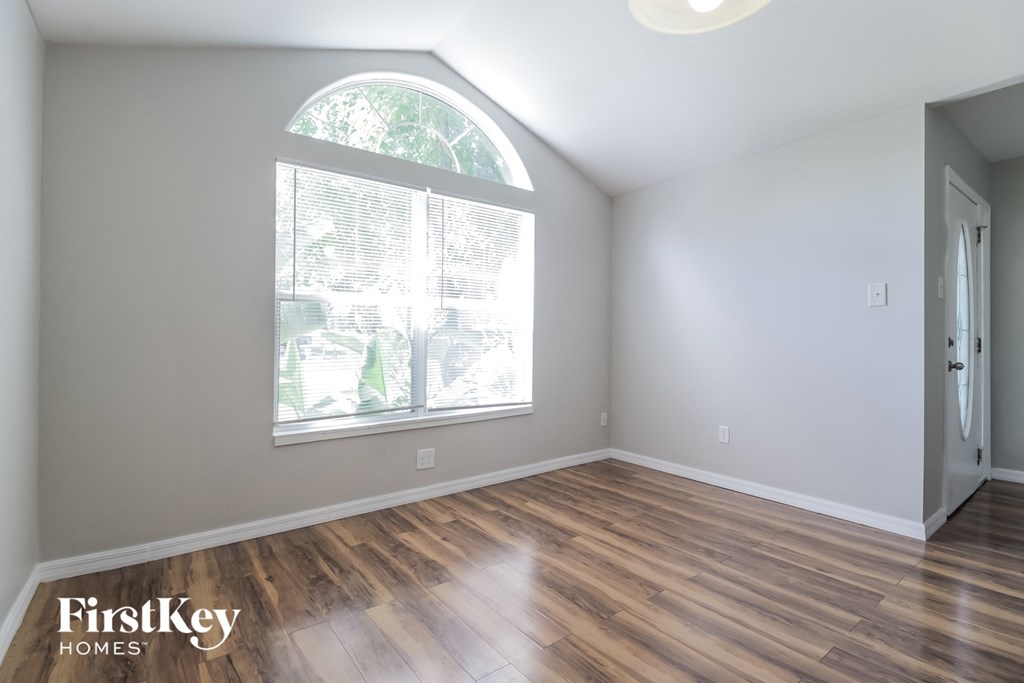 the living room of an empty house with wood floors and a large window