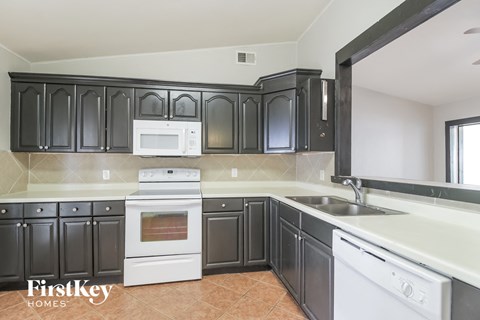an empty kitchen with black cabinets and white appliances