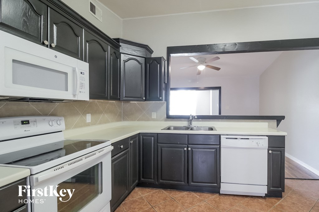 an empty kitchen with white appliances and black cabinets