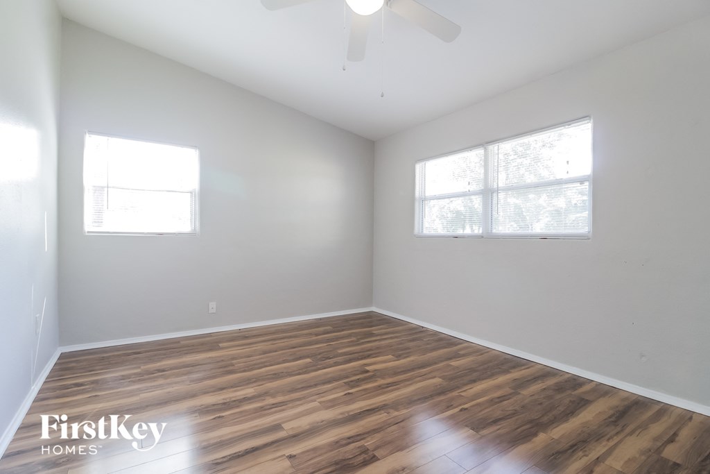 a bedroom with white walls and wood flooring and a ceiling fan