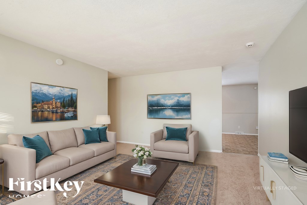 A living room with a couch, a coffee table, and two paintings on the wall.