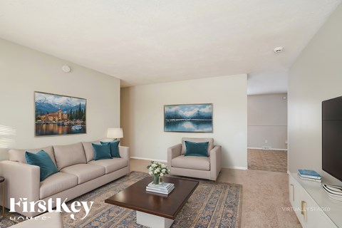 A living room with a couch, a coffee table, and two paintings on the wall.