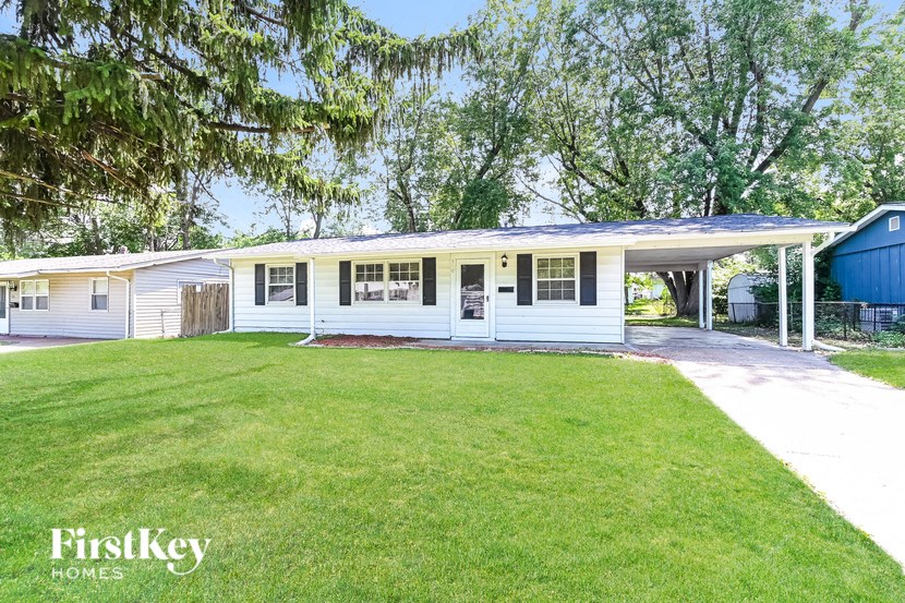 a white house with a lawn and a blue shed