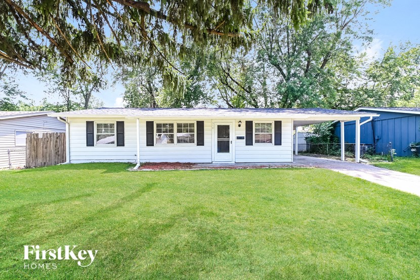 a white house with a lawn and a blue shed