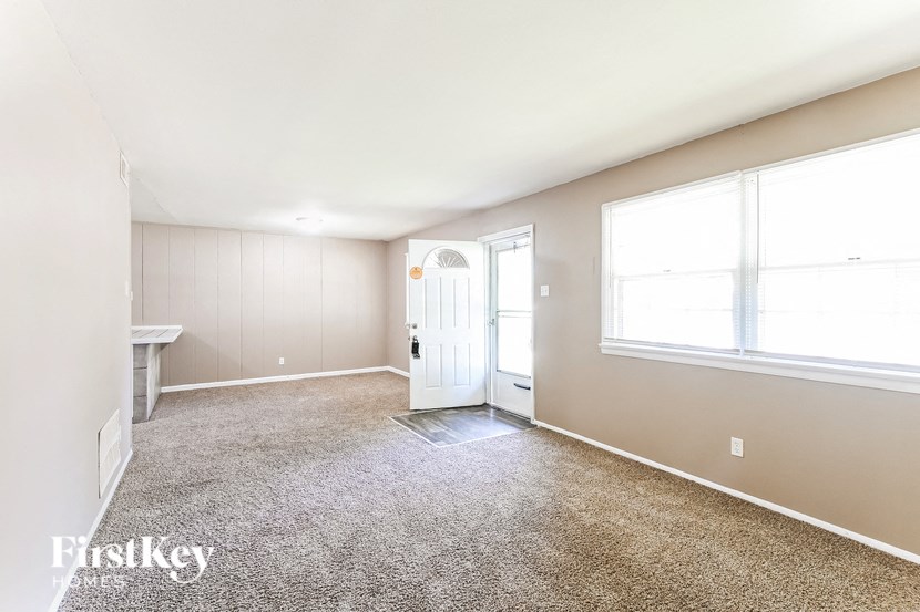 an empty living room with a white door and a window