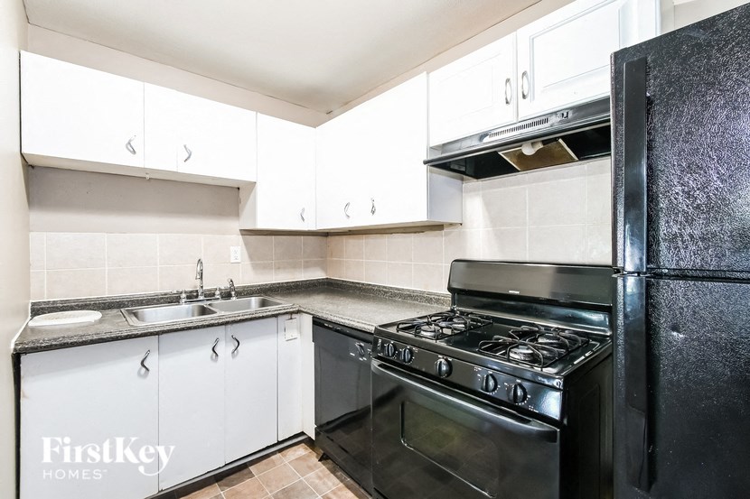 a kitchen with white cabinets and a black stove and refrigerator
