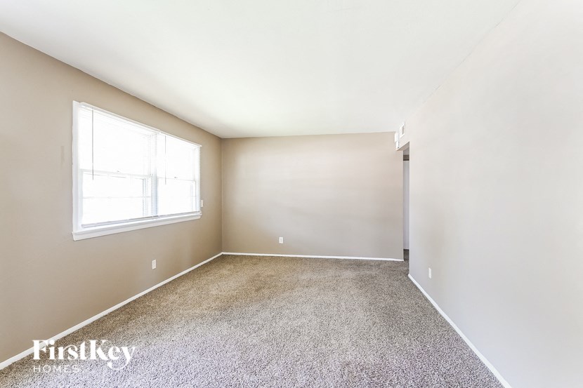 an empty room with a window and carpet