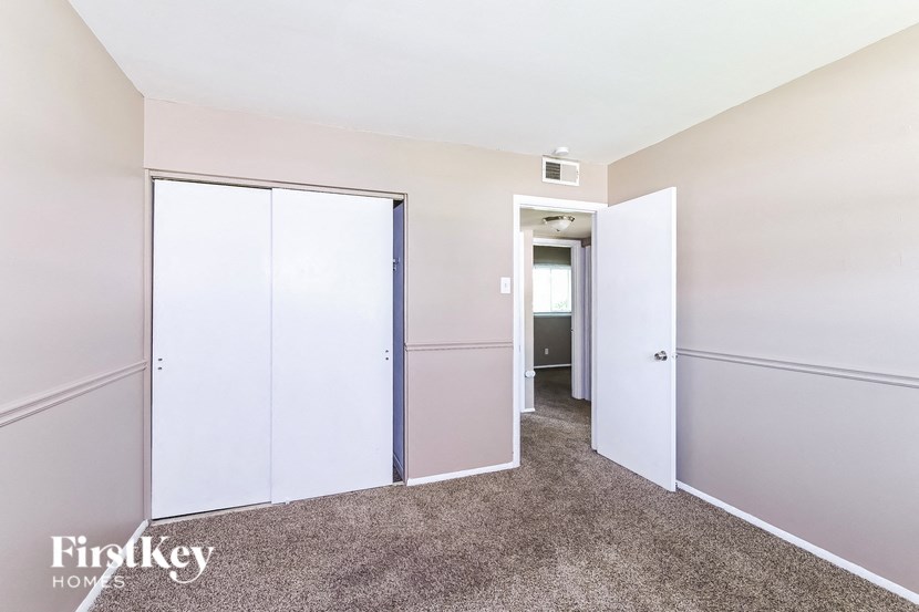 a bedroom with white closets and a carpeted floor