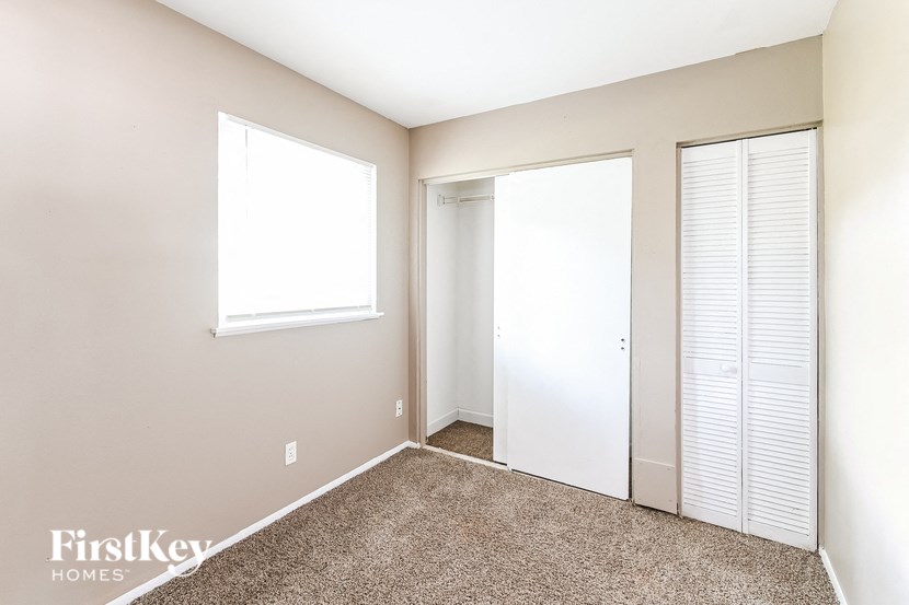 a bedroom with two closets and a window and a carpeted floor
