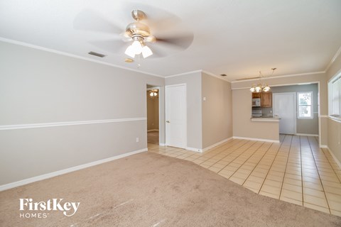 A spacious room with a ceiling fan and beige carpeting.