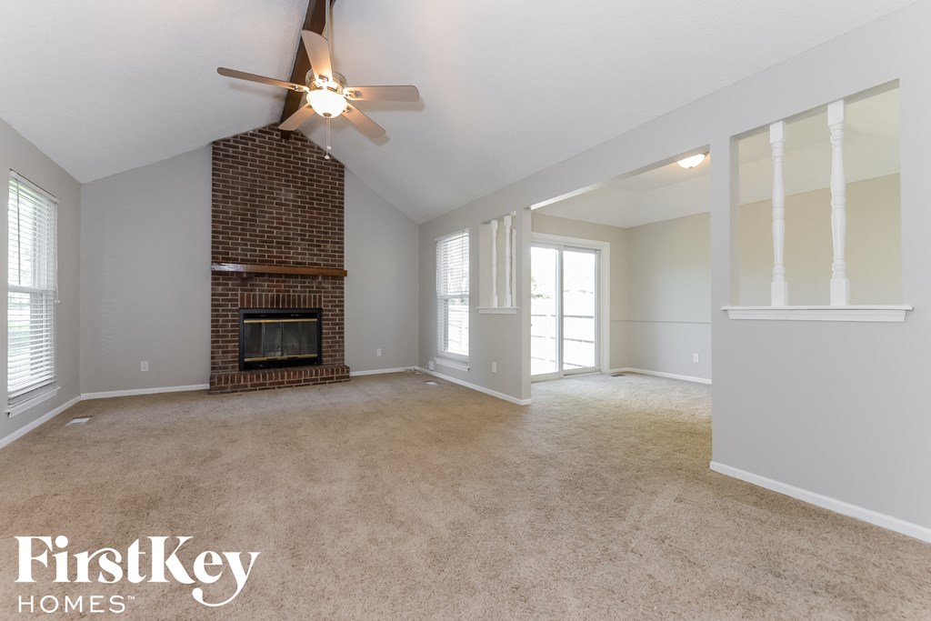 A spacious living room with a fireplace and a ceiling fan.
