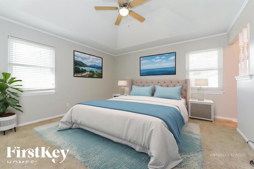 A bedroom with a bed, a ceiling fan, and two pictures on the wall.