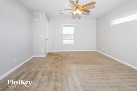 the spacious living room with carpet and a ceiling fan
