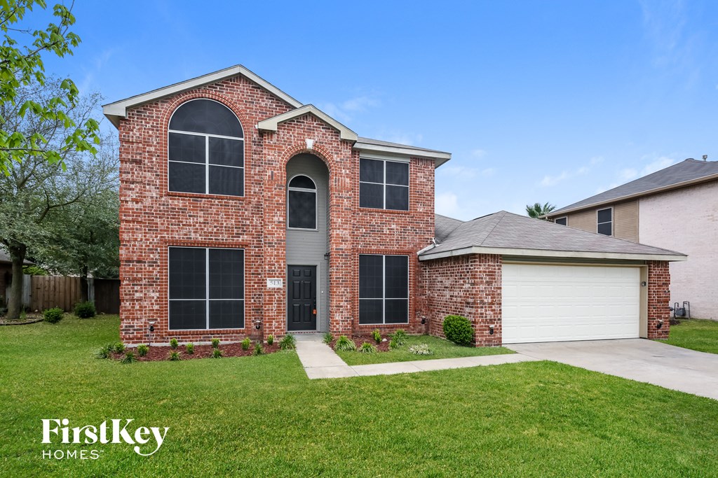 a brick house with a white garage and a green lawn