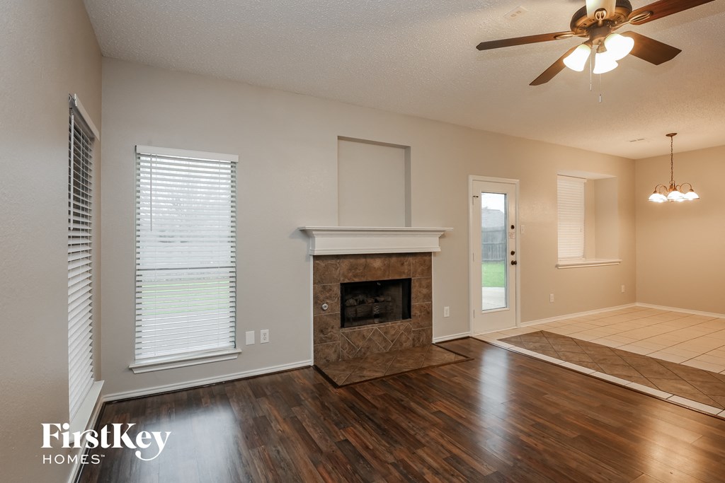 an empty living room with a fireplace and a ceiling fan