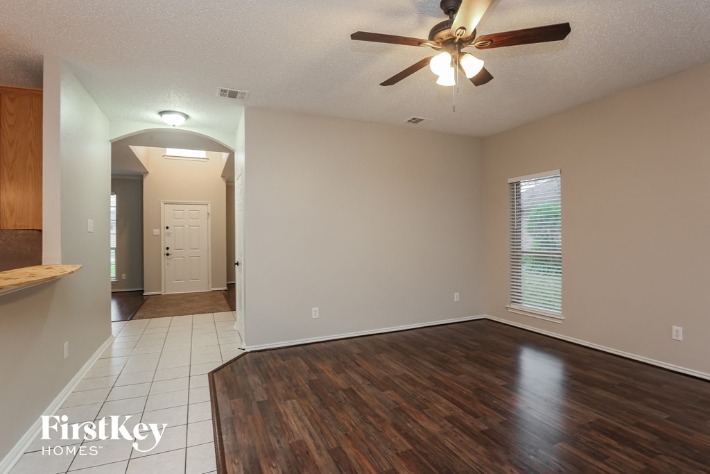 an empty living room with wood flooring and a ceiling fan