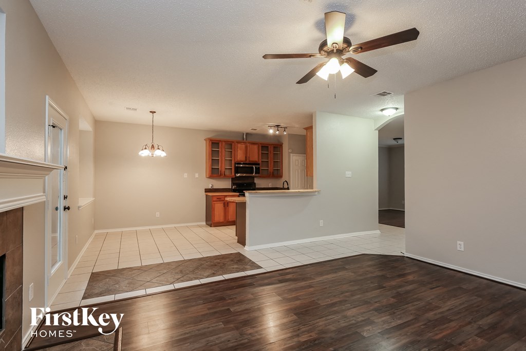 an empty living room and kitchen with a ceiling fan