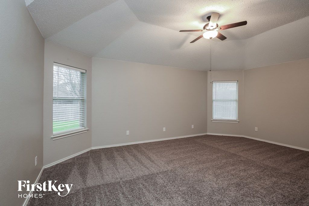 the spacious living room with carpeted flooring and a ceiling fan
