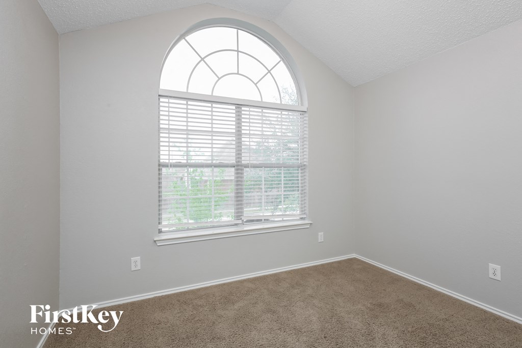an empty room with a large window and carpet