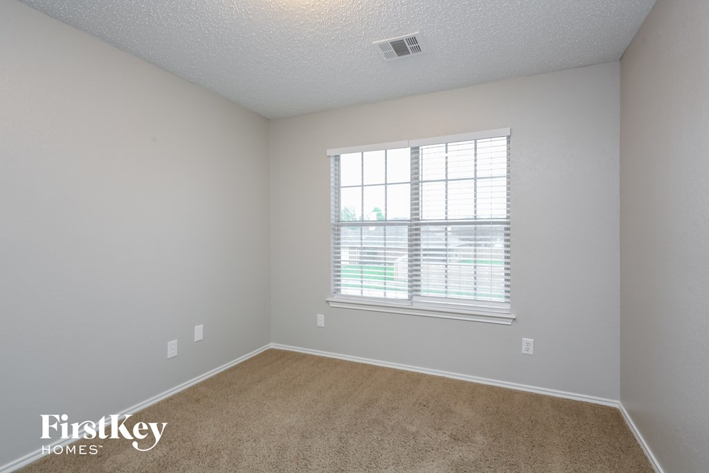 a spacious bedroom with a large window and carpeting