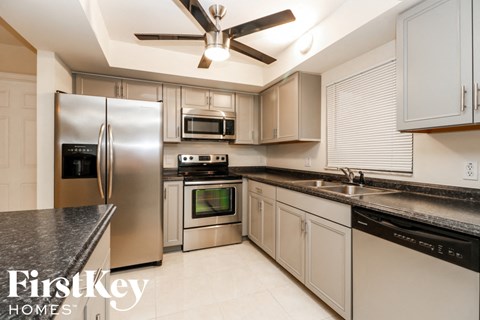 A modern kitchen with a stainless steel refrigerator and a ceiling fan.