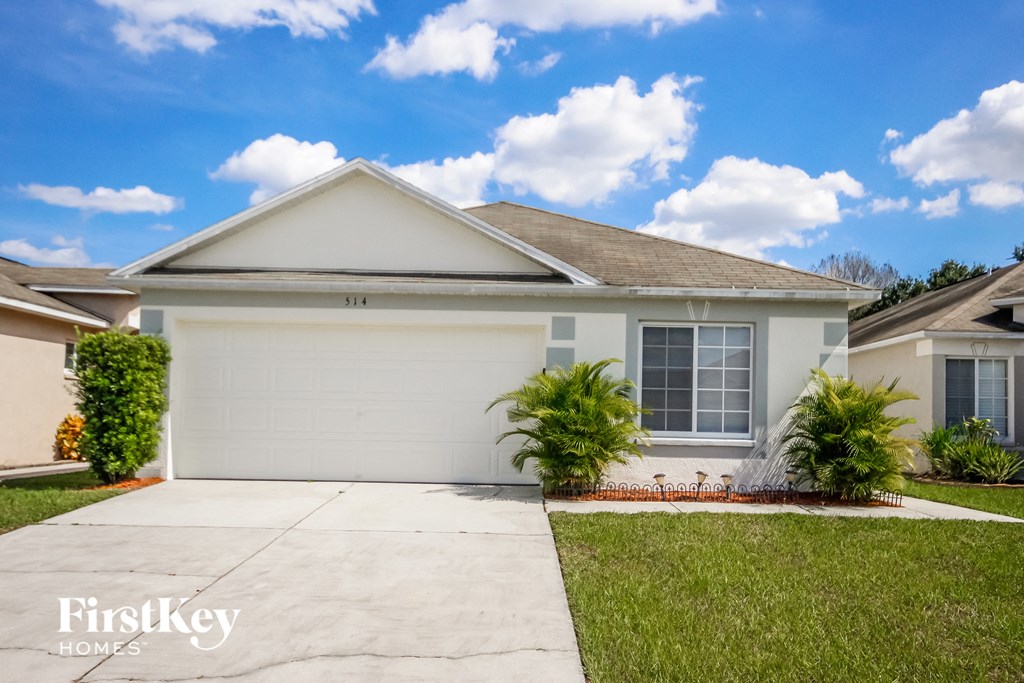 a white house with a garage door and a lawn