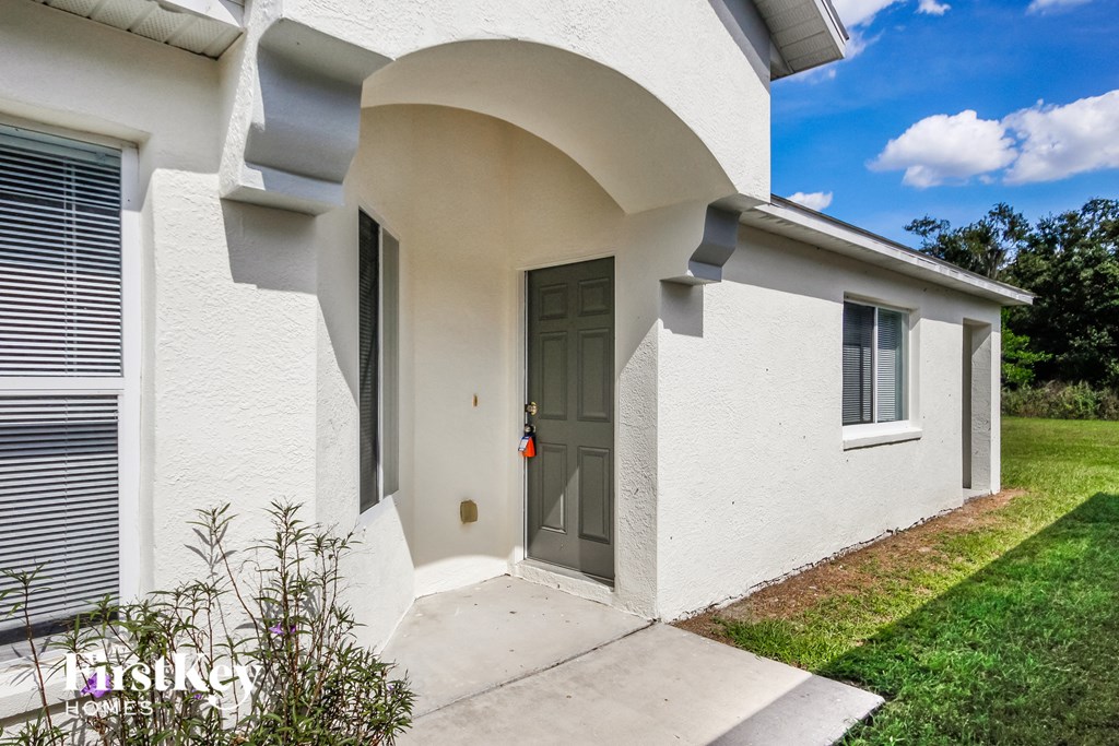 the front entrance to a white house with a green door