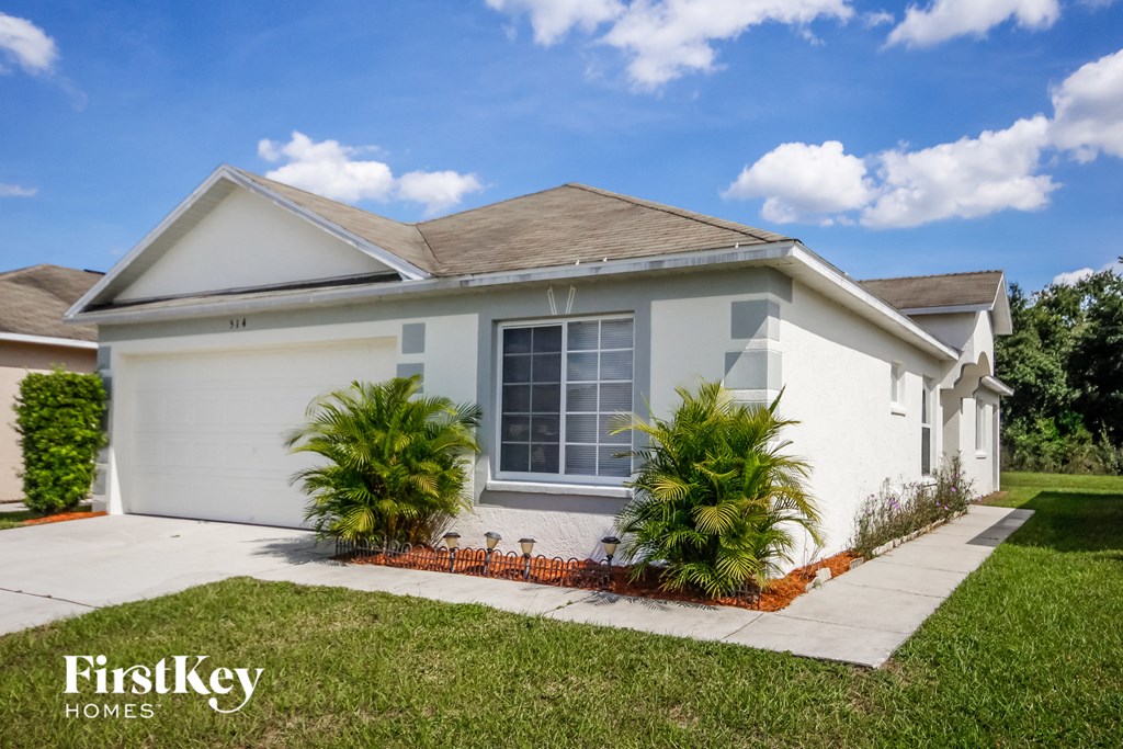 a white house with a lawn and palm trees